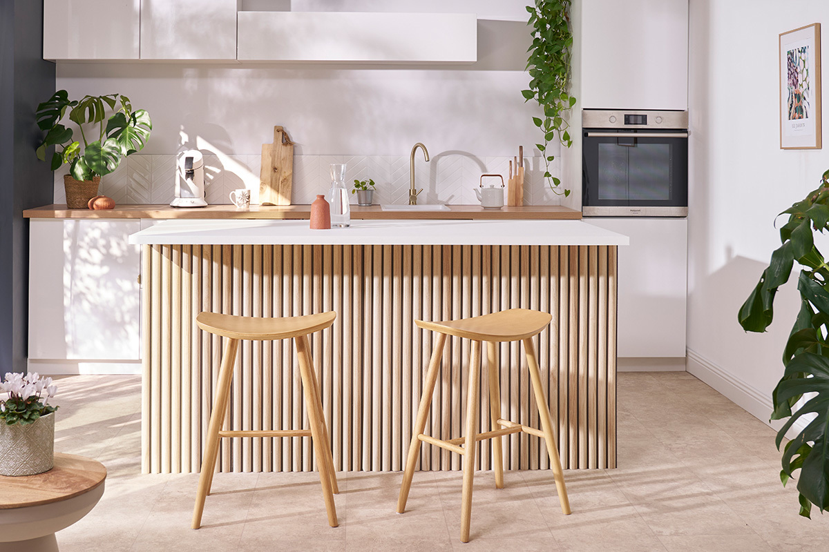Tabourets de bar en bois clair devant un �lot de cuisine moderne.