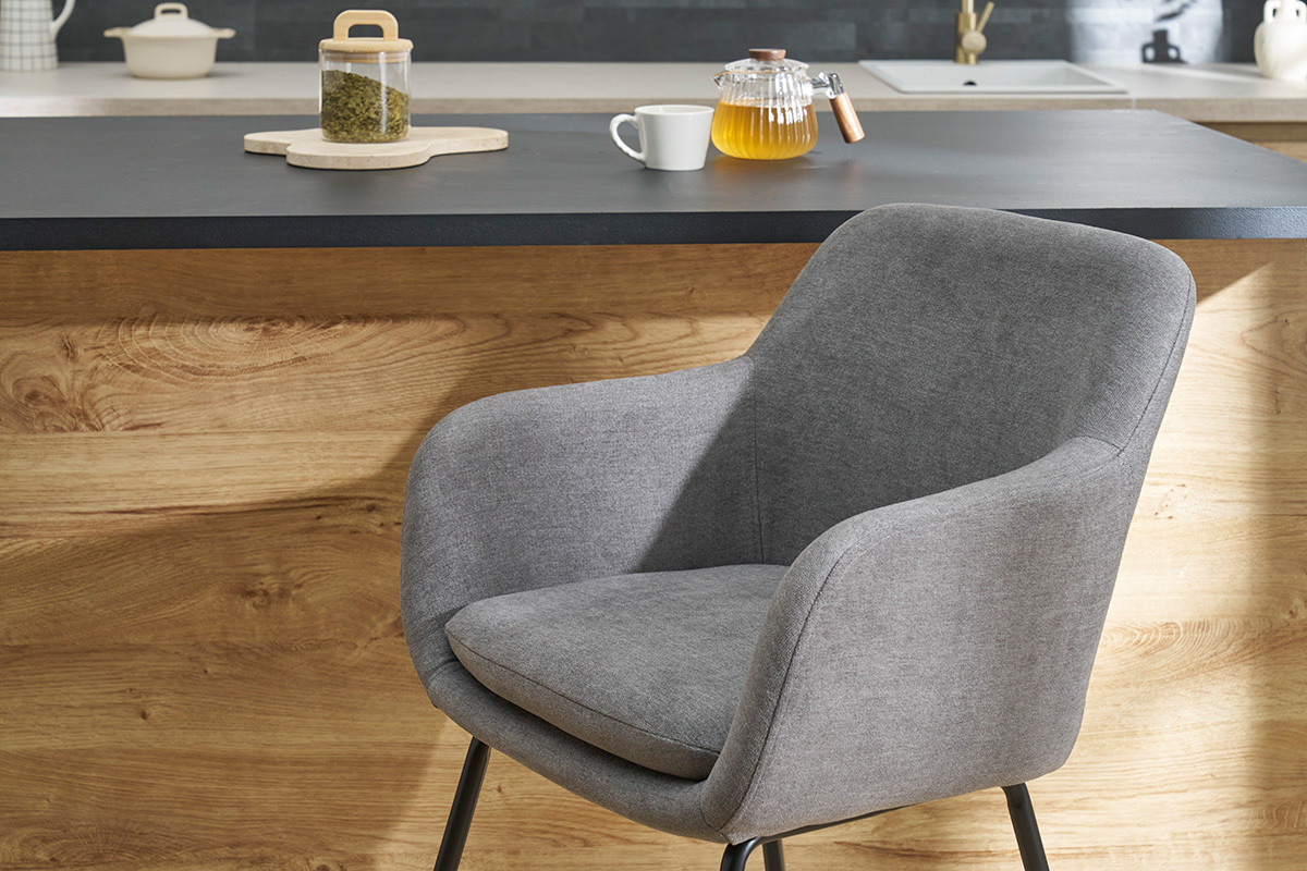 Tabouret de bar en tissu gris effet velours avec assise rembourr�e devant un comptoir en bois.