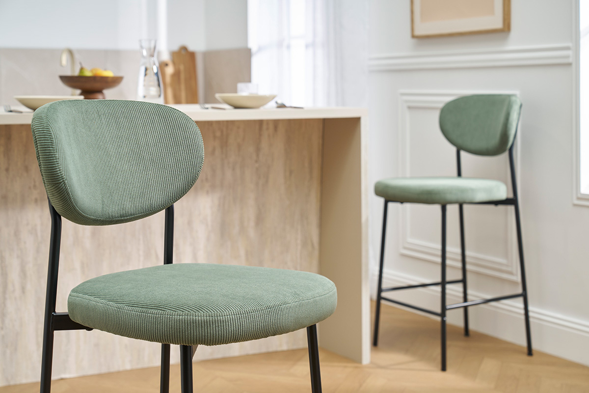 Tabourets de bar vert kaki en velours avec pieds en m�tal noir devant un �lot de cuisine.