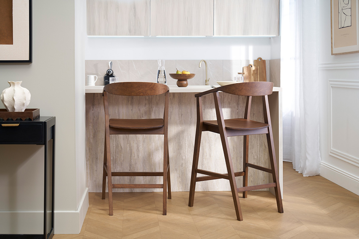 Deux tabourets de bar scandinaves en bois fonc� BAHIA devant un �lot de cuisine.
